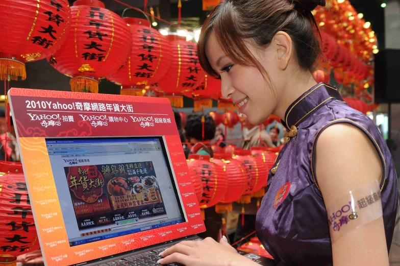 a woman standing in front of a laptop with decorations hanging over her head