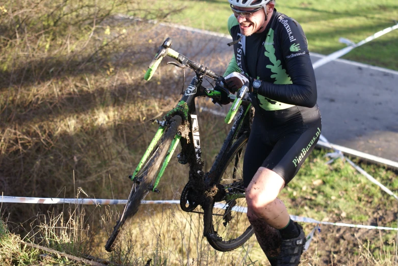 a cyclist takes his bike through the mud