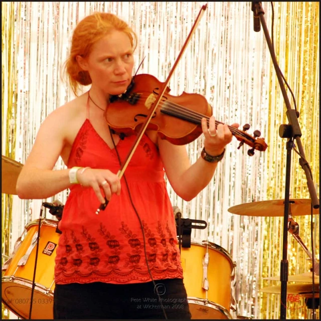 a woman in a red shirt is playing the violin