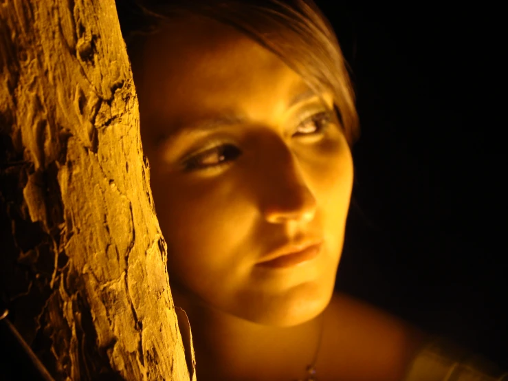 a woman is staring from behind a tree