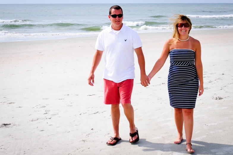 a man and woman holding hands walking on the beach