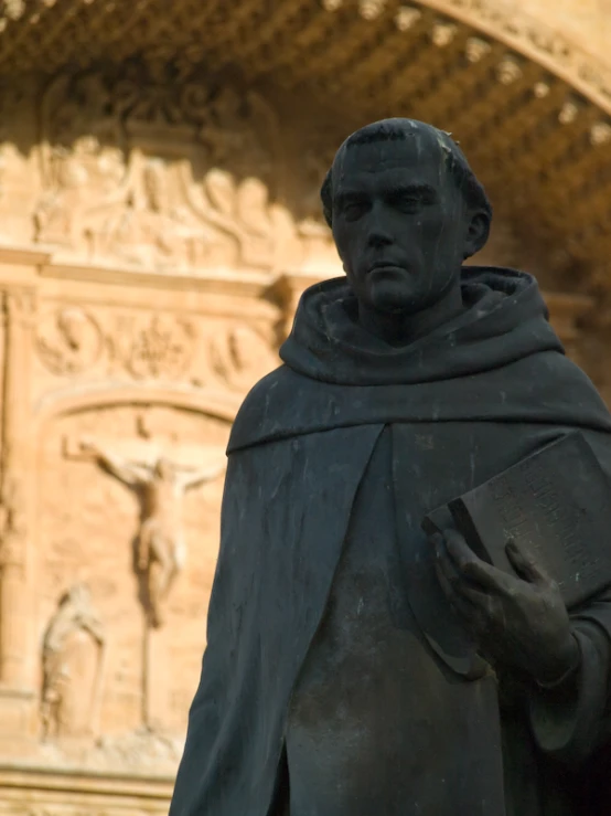 a statue of a man holding a book with one hand and a book in his other