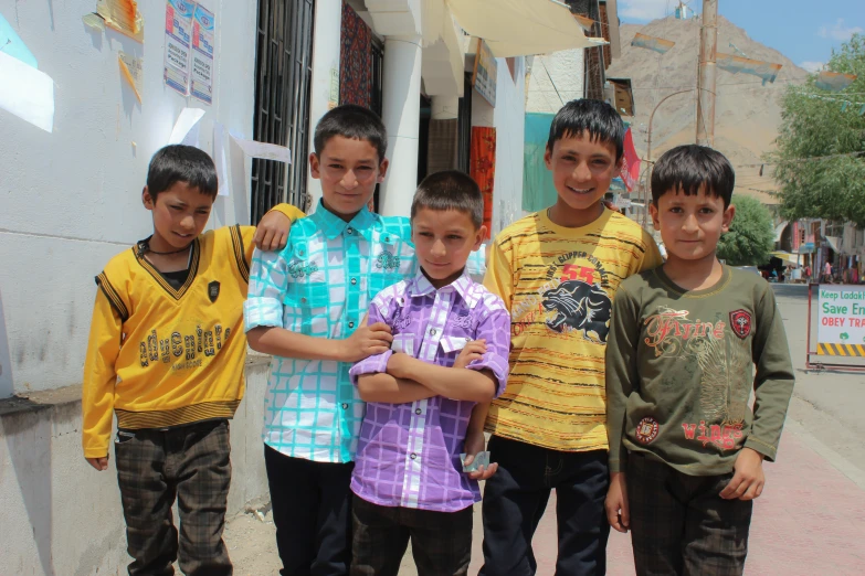 a group of boys in colorful clothing standing in the street