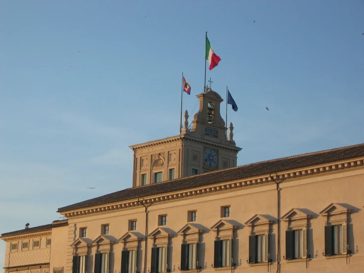 an old building that has several flags flying in the wind