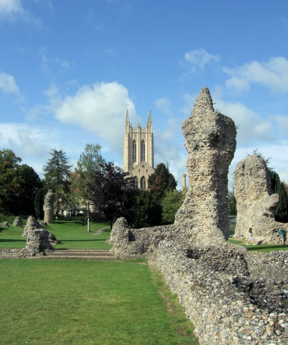 the spire and clock tower of a church towering over an area with grass