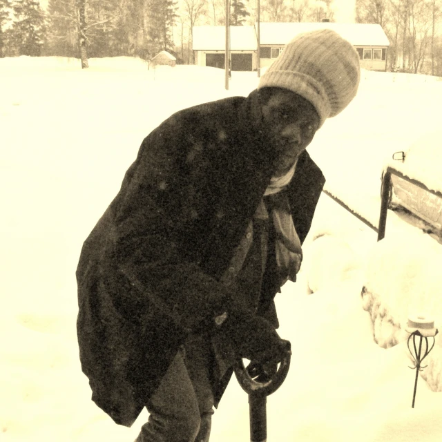 a man standing on a snowy field near a fence