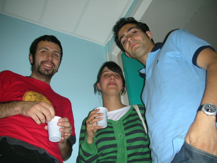 three people holding cups while standing near each other