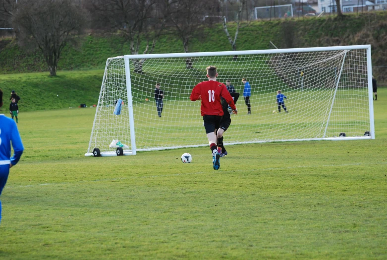 a soccer goalie looks down at the ground as others walk by