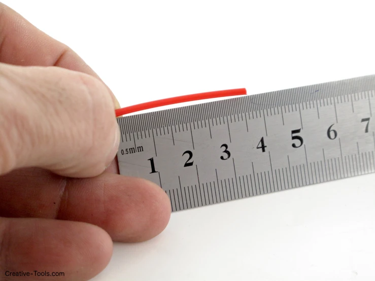 a ruler with numbers on it is being held by someone's finger