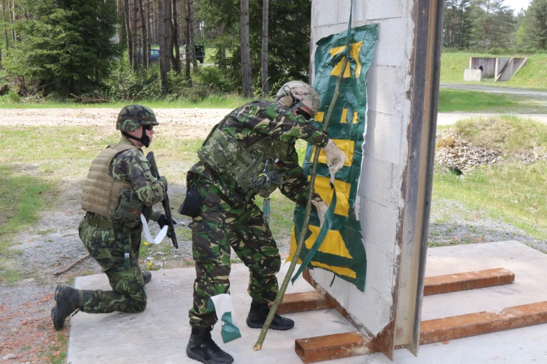 the two soldiers are in military garb working on a sign