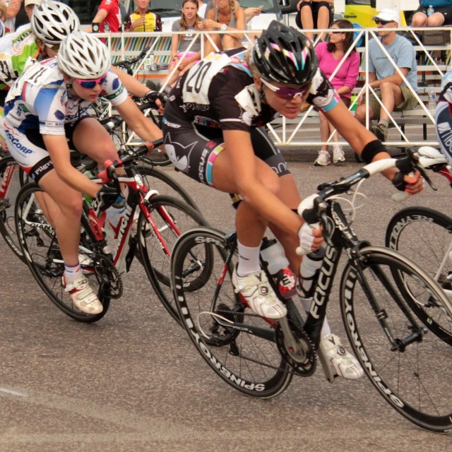 four cyclists are racing down the road on bicycles