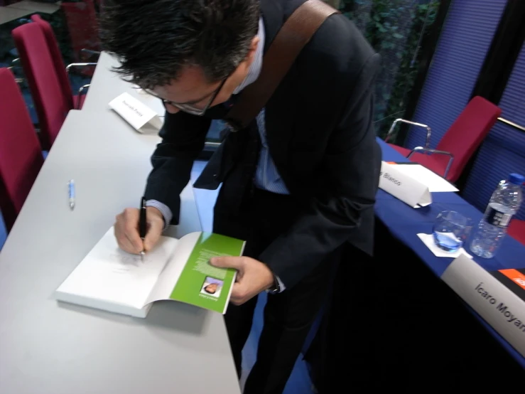 a man in a suit writing on an open notebook