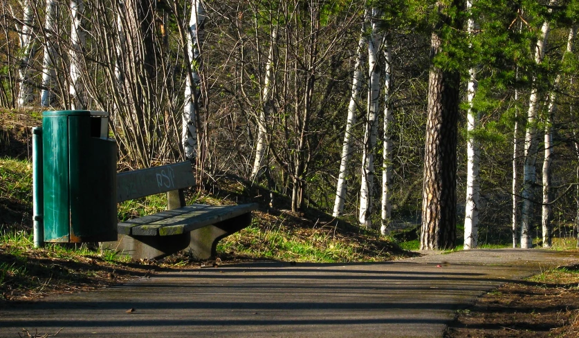 a wooden bench on the side of a dirt road