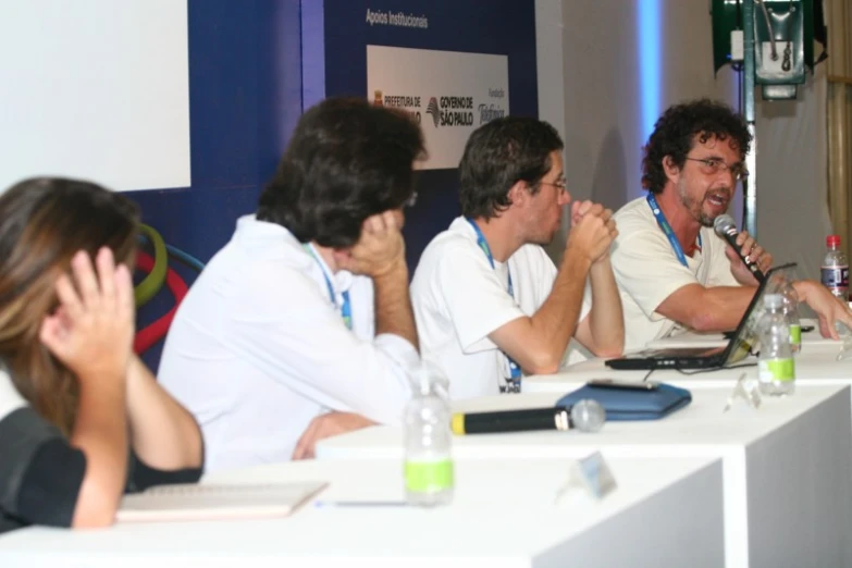 five people sitting at a table listening to someone