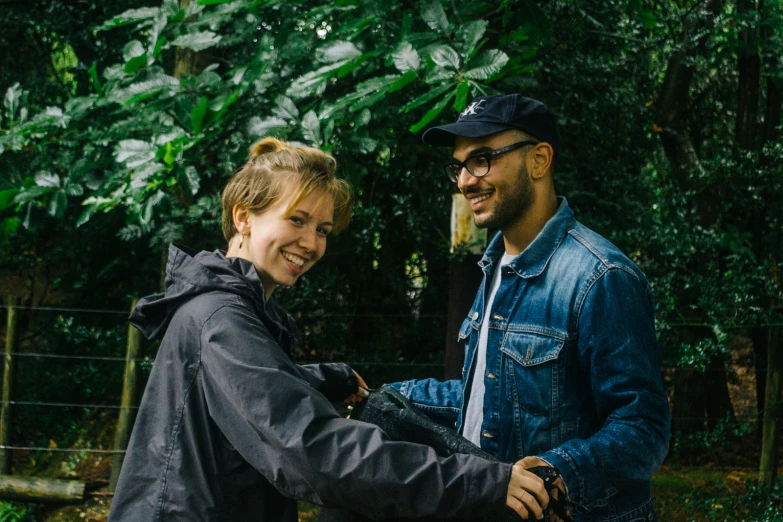 a man and woman standing together near trees