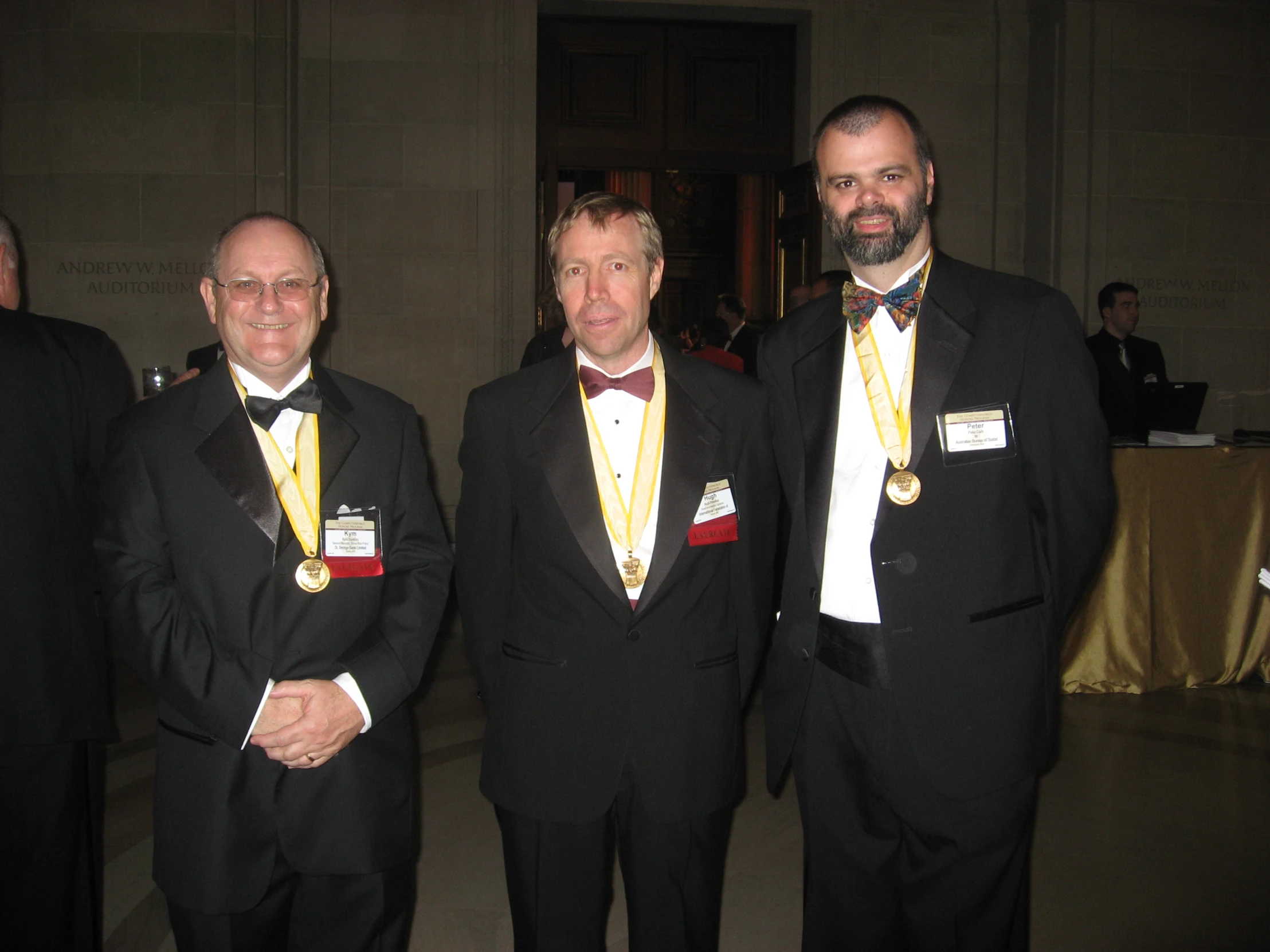 three men in tuxedos and vests standing next to each other