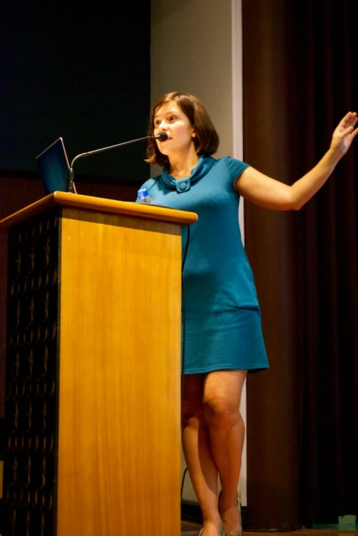 woman speaking at podium with open laptop computer