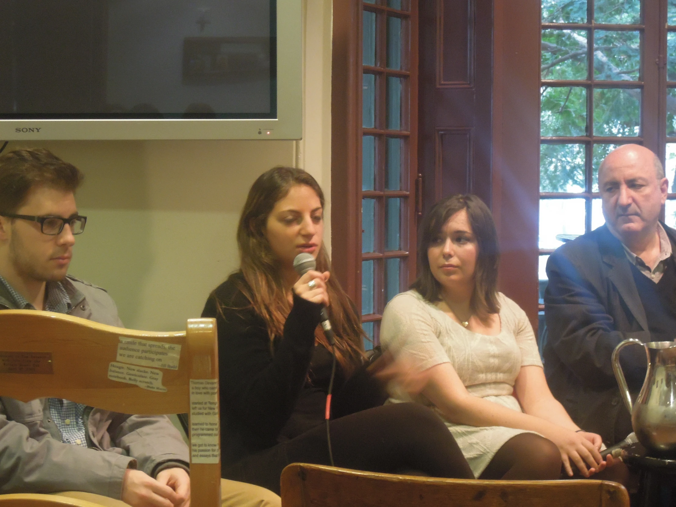 three people sitting on a chair holding a microphone