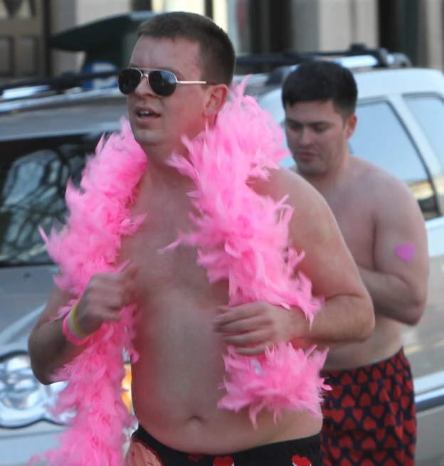 a man with bright pink feathers is on the street