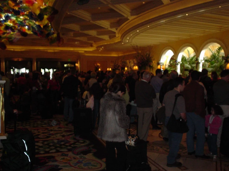 a crowd of people standing around in the middle of a hallway