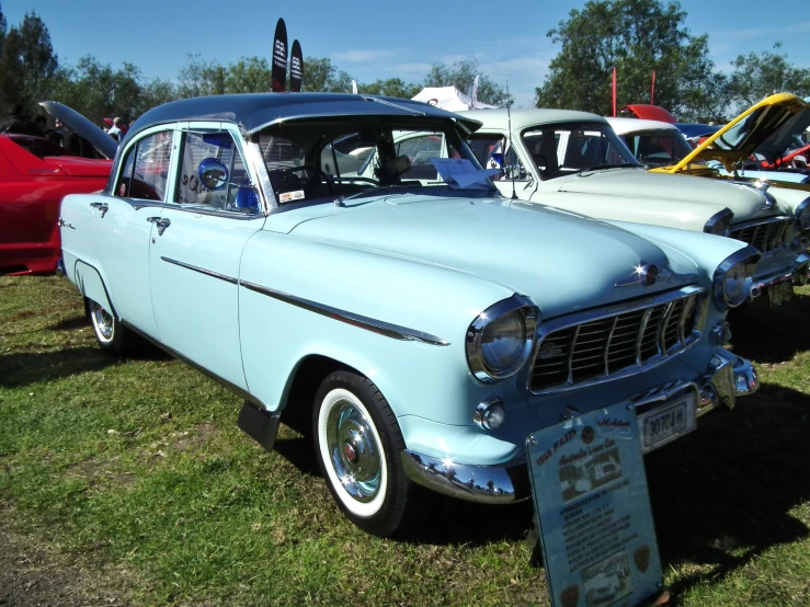 the old car is blue and parked in the grass