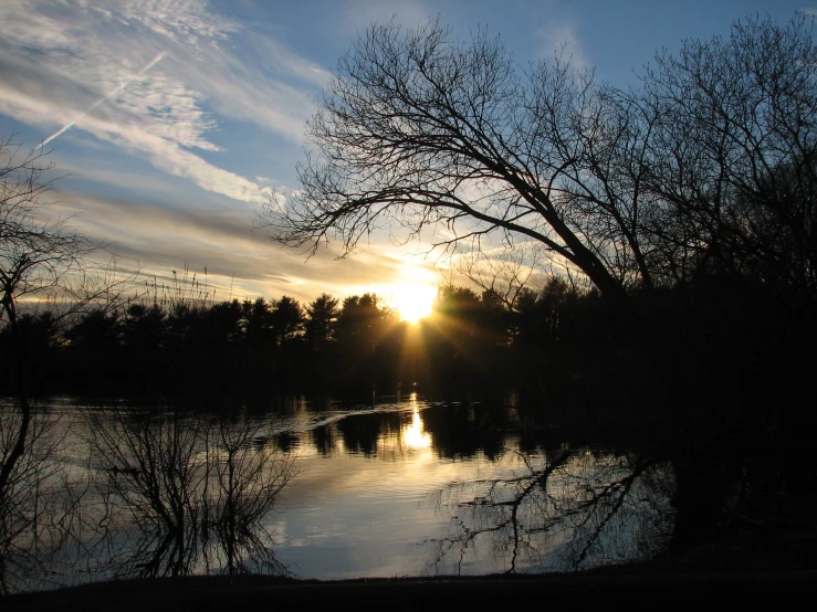 the sun is setting over a river with water reflections