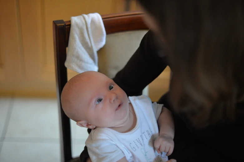 baby smiling in chair next to woman's arm