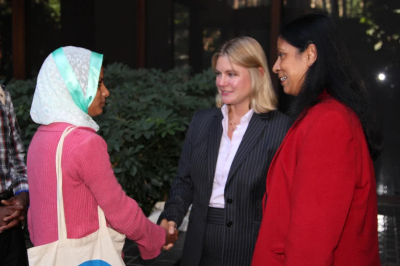 some women holding hands while smiling at one another