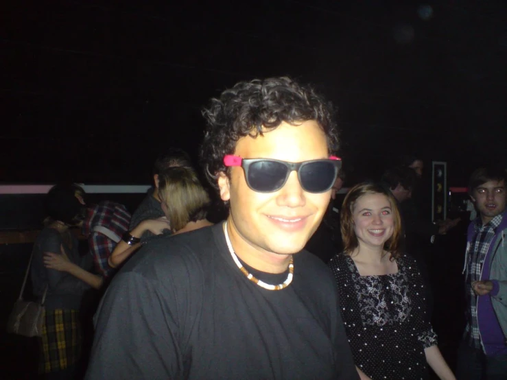 a man with sunglasses posing for a po with other people