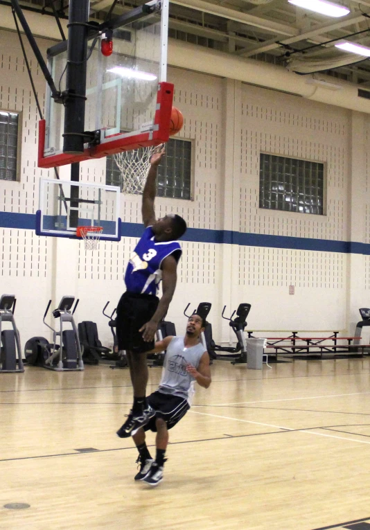 two young men are playing basketball inside an indoor gym