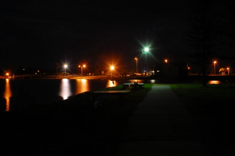 the night view looking down the sidewalk beside a lake