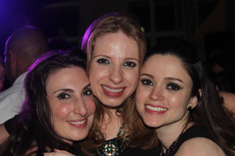 two women are hugging and smiling together in a party