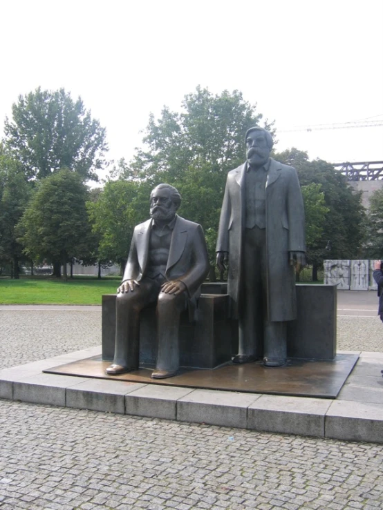 the two statues show men sitting in a bench