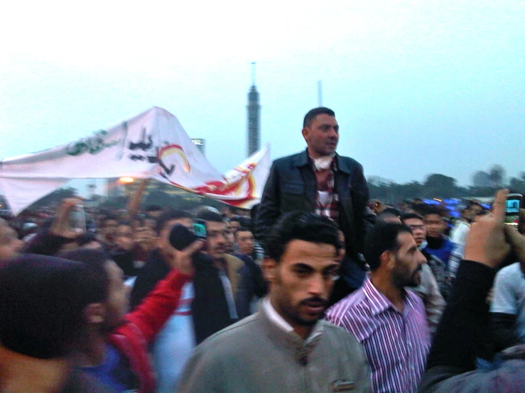 man standing up on his shoulders among other crowd members