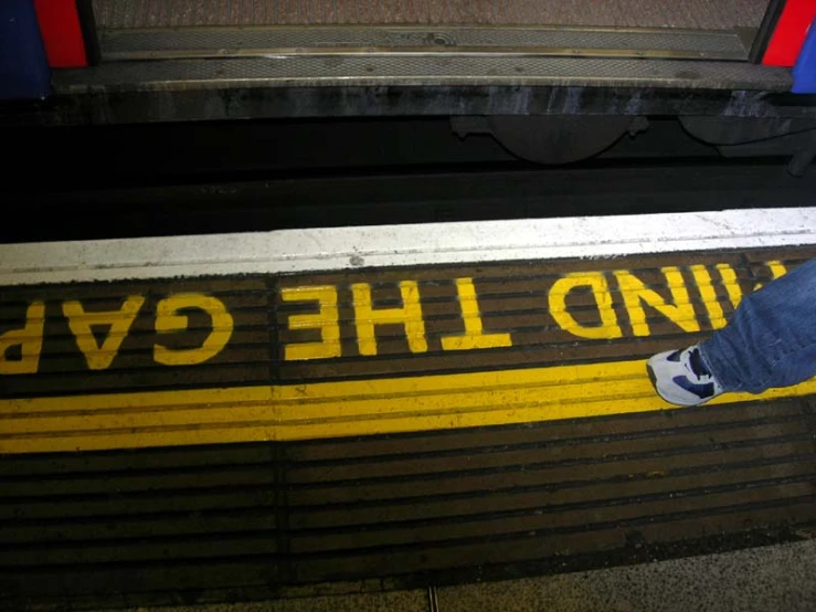 a person standing on a train platform with their foot near the curb