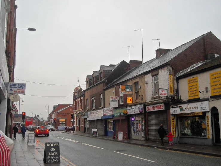 people walk on the sidewalk along the road in the rain