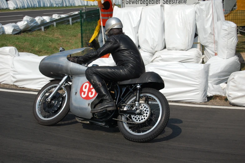 a man in black leather riding a silver motorcycle