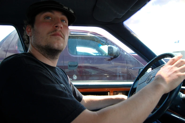 a man in a black shirt driving in his car