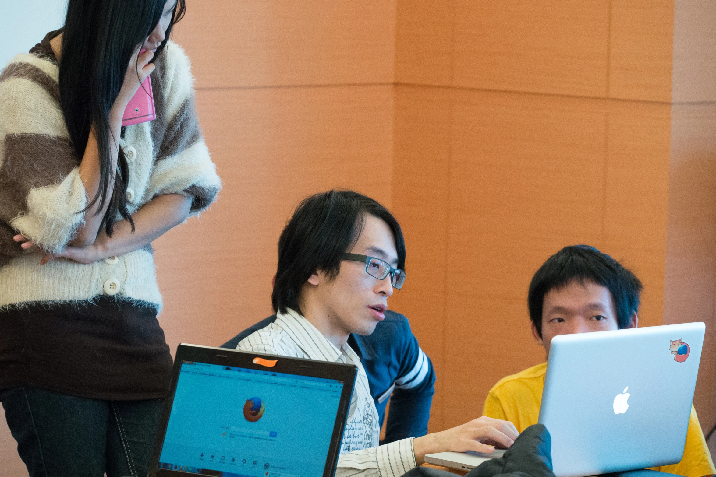 two people sitting at a table working on laptops