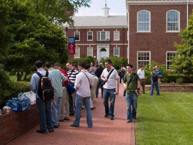 many students outside a large building with a clock on the building