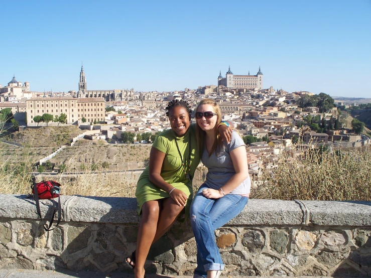 two women are sitting on the ledge of a hill