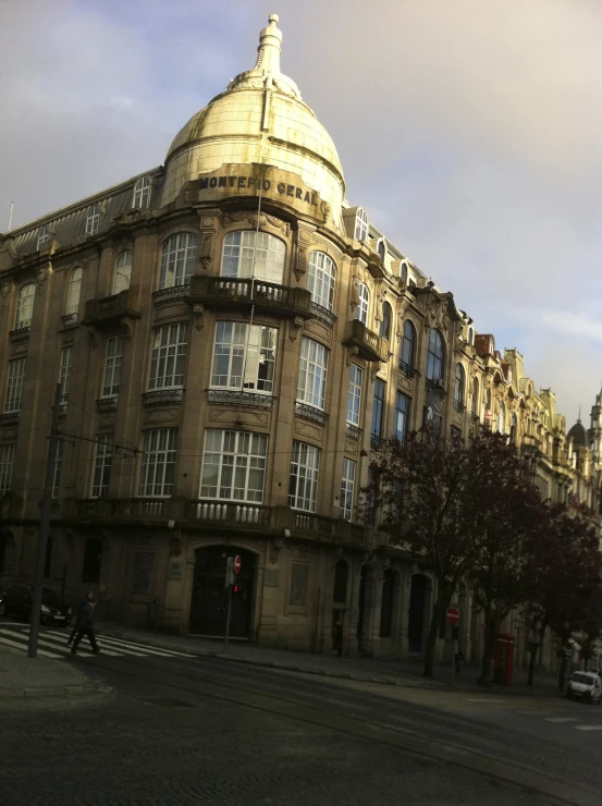 a tan building with a gold dome with people walking