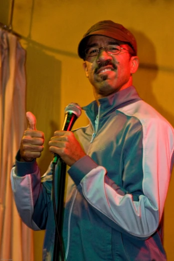 a man stands in front of a microphone giving a thumbs up