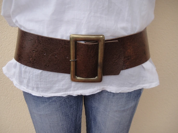 a woman is wearing a brown belt while wearing white shirt