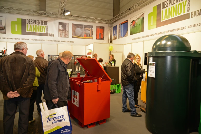 people at a trade exhibition talking and some are standing by a waste can