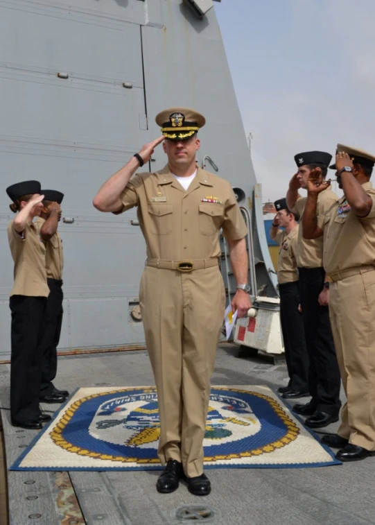 many navy personnel standing around and saluting