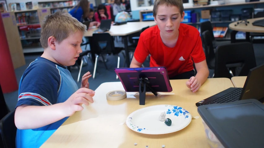 two s sit in front of a tablet computer