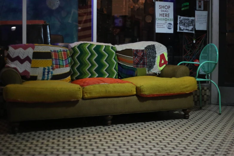 a yellow and green couch sits on the floor of a storefront