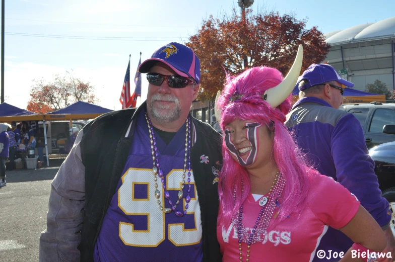 the man in the purple shirt is wearing a pink wig and a horned head