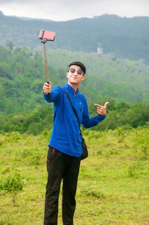 a man with blue jacket holding an object up in front of his face